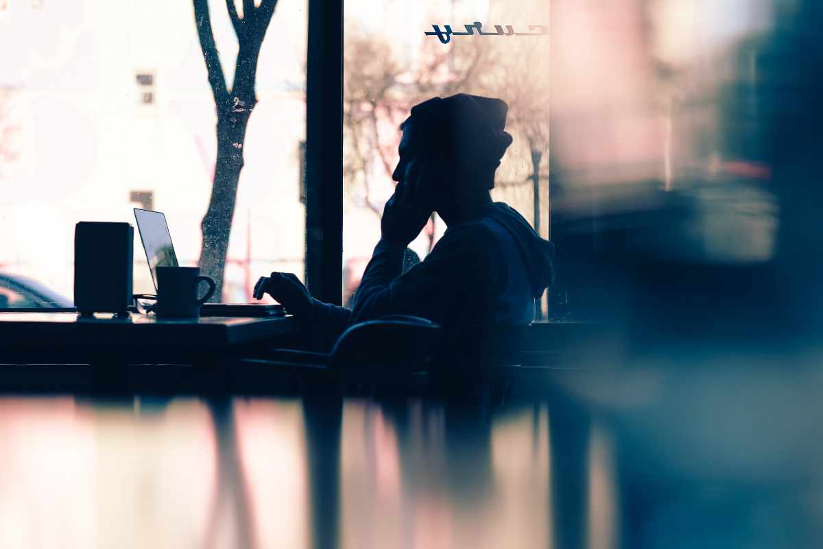 Small business owner sitting at a cluttered desk looking overwhelmed while working on a laptop