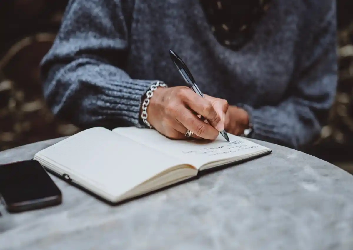 Business owner writing in a journal to reflect on ideas and goals