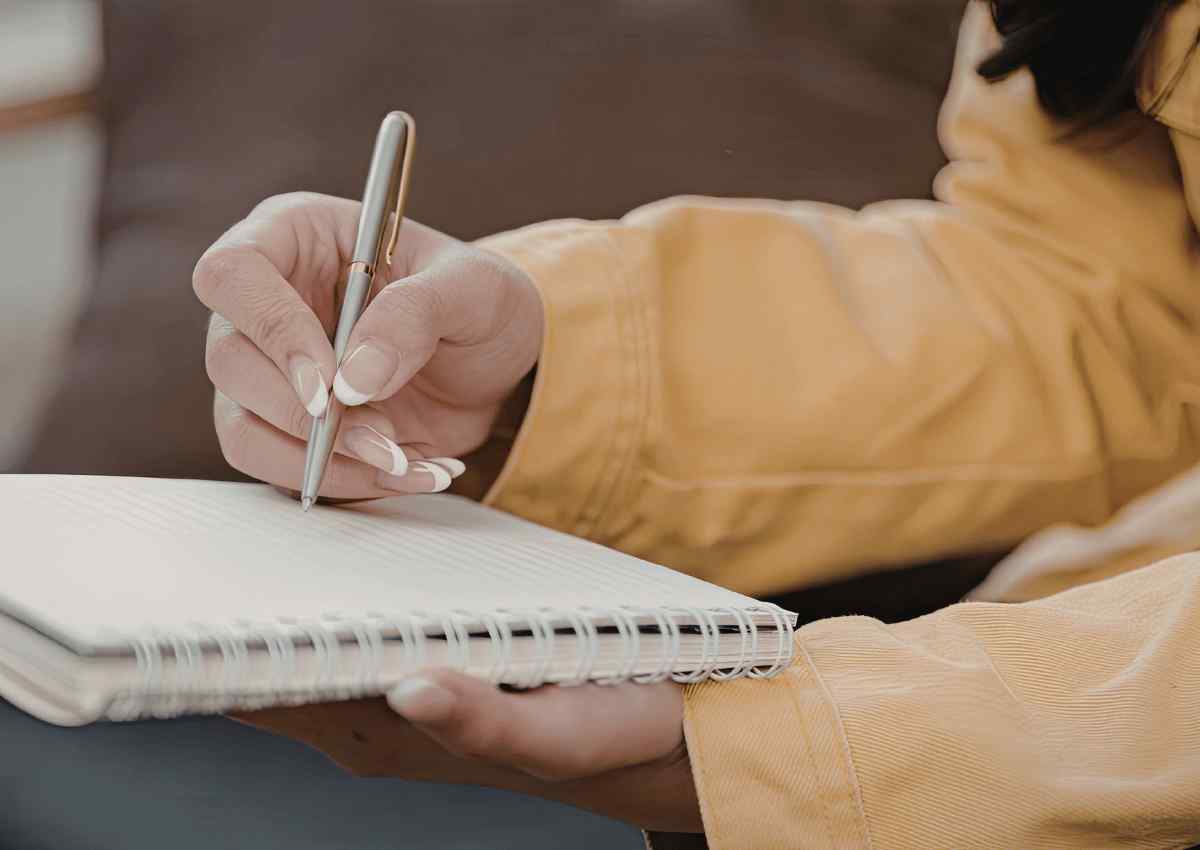 Person writing in a journal in soft natural light, reflecting on business goals and personal growth