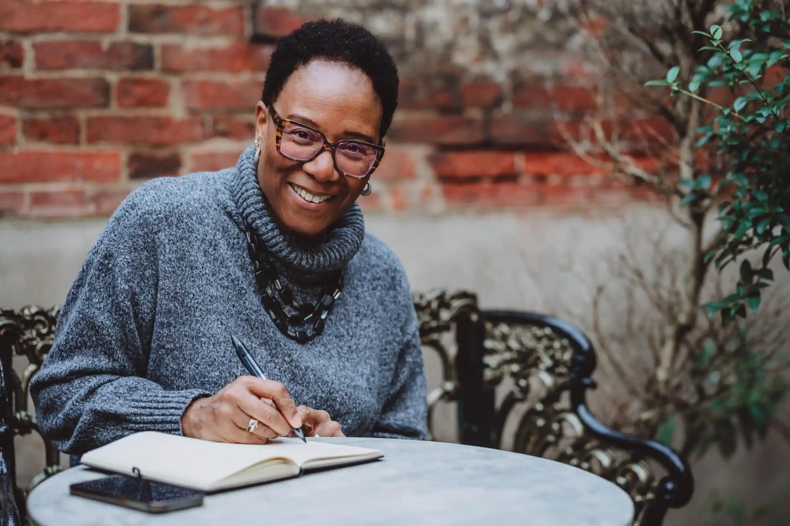 Business coach Val Mattinson sitting with a notebook in a relaxed setting, reflecting and making notes.